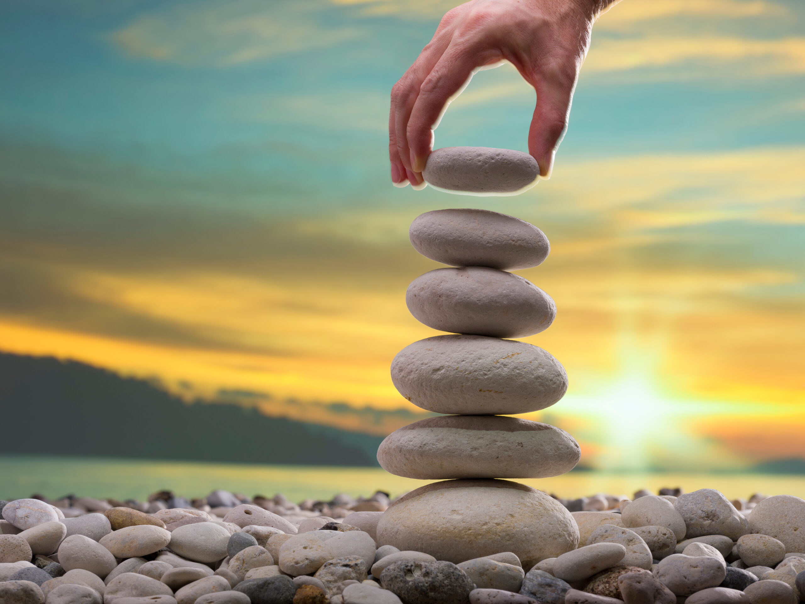 The man’s hand is putting gravel on the stone tower. Personal De